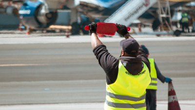 Ground crew directing aircraft on runway at airport terminal