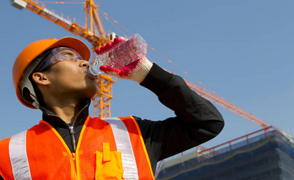 A construction worker drinks water to stay hydrated at the job site